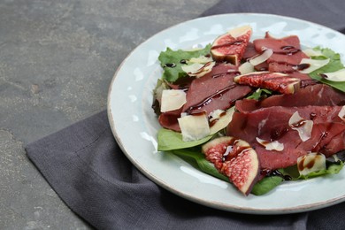 Plate with delicious bresaola salad on grey textured table, closeup. Space for text