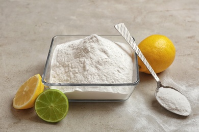 Photo of Bowl and spoon of baking soda with lemons on gray table