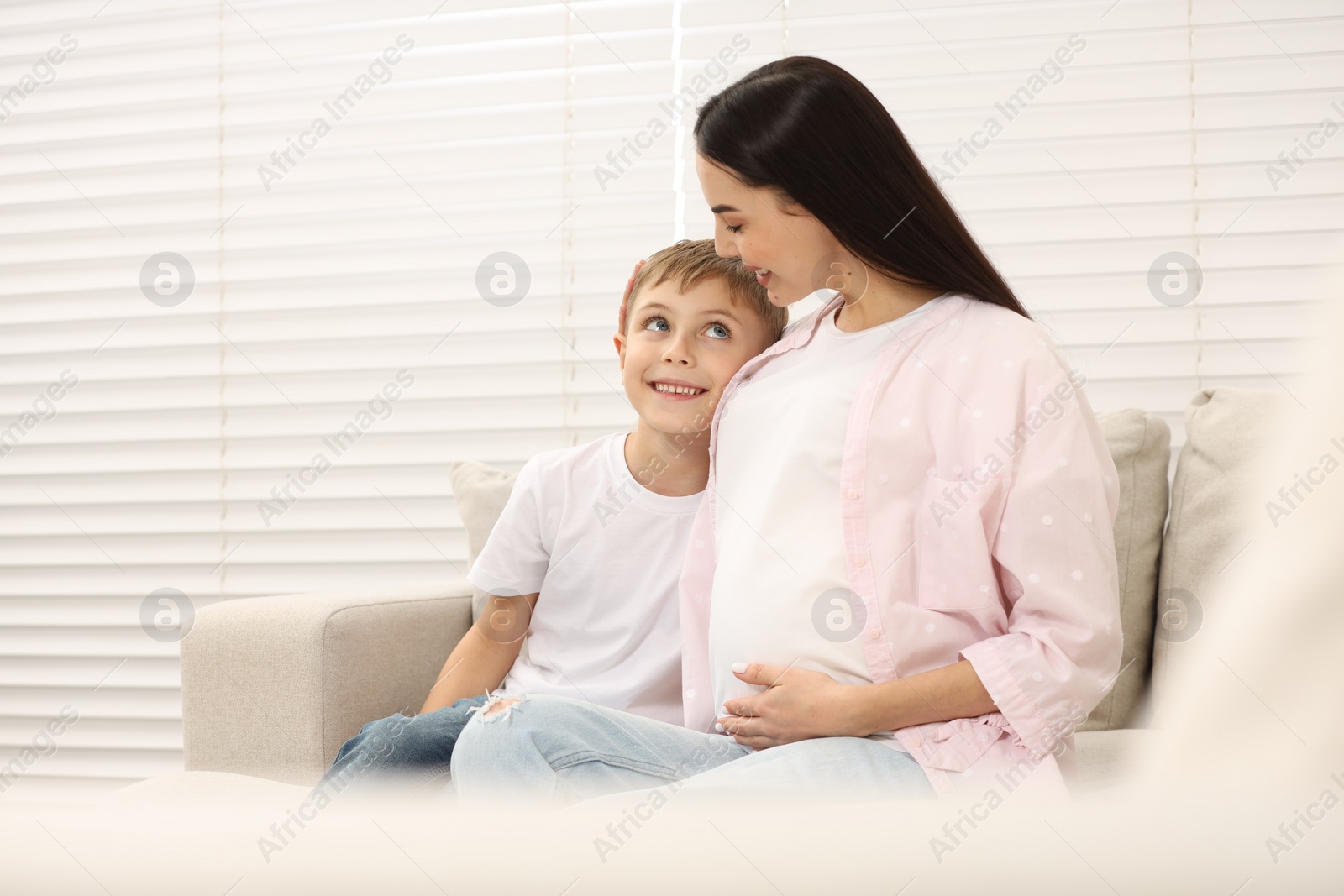 Photo of Happy pregnant woman spending time with her son at home