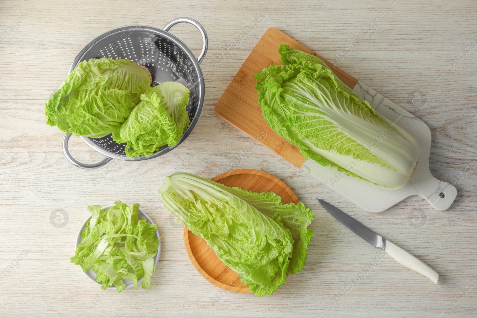 Photo of Whole and cut fresh ripe Chinese cabbages on white wooden table, flat lay