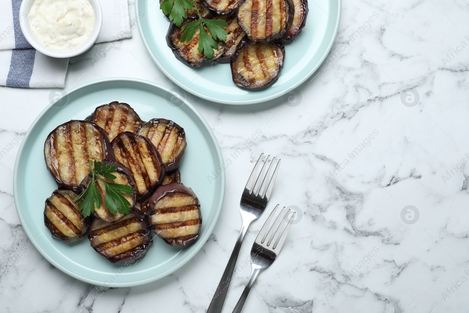 Photo of Delicious grilled eggplant slices and sauce on white marble table, flat lay. Space for text
