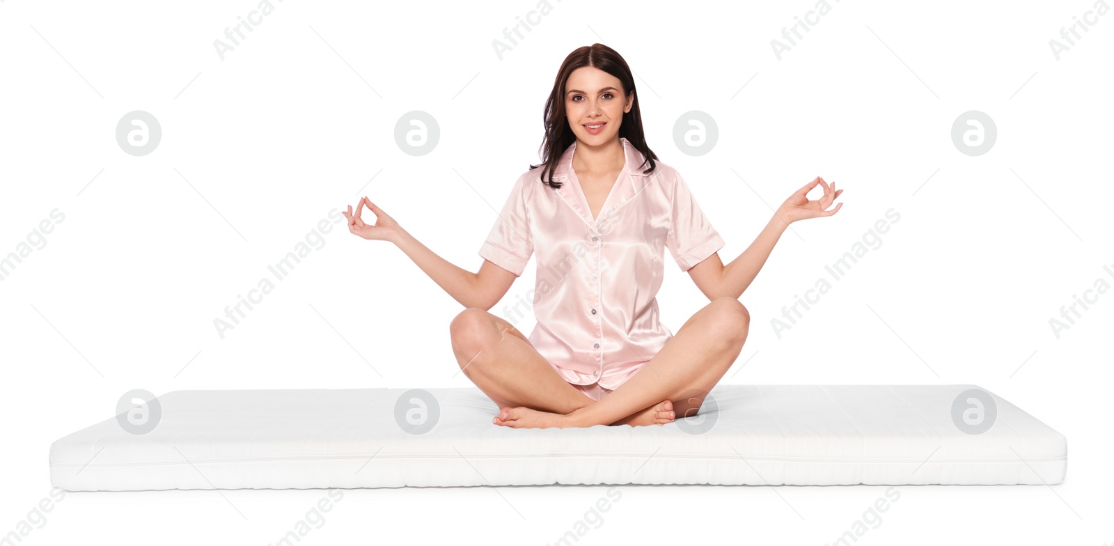 Photo of Young woman meditating on soft mattress against white background