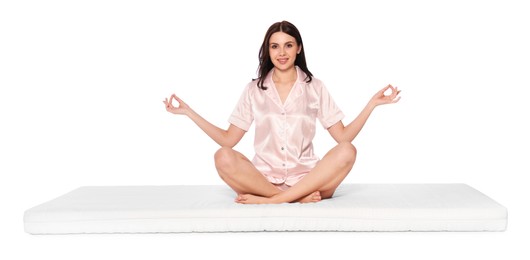 Young woman meditating on soft mattress against white background