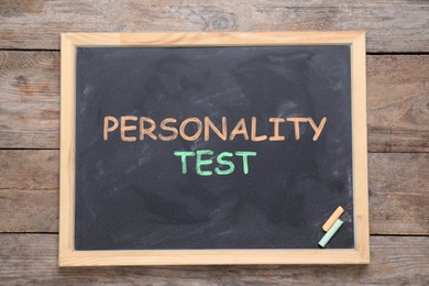 Image of Blackboard with text Personality Test and pieces of color chalk on wooden background, top view