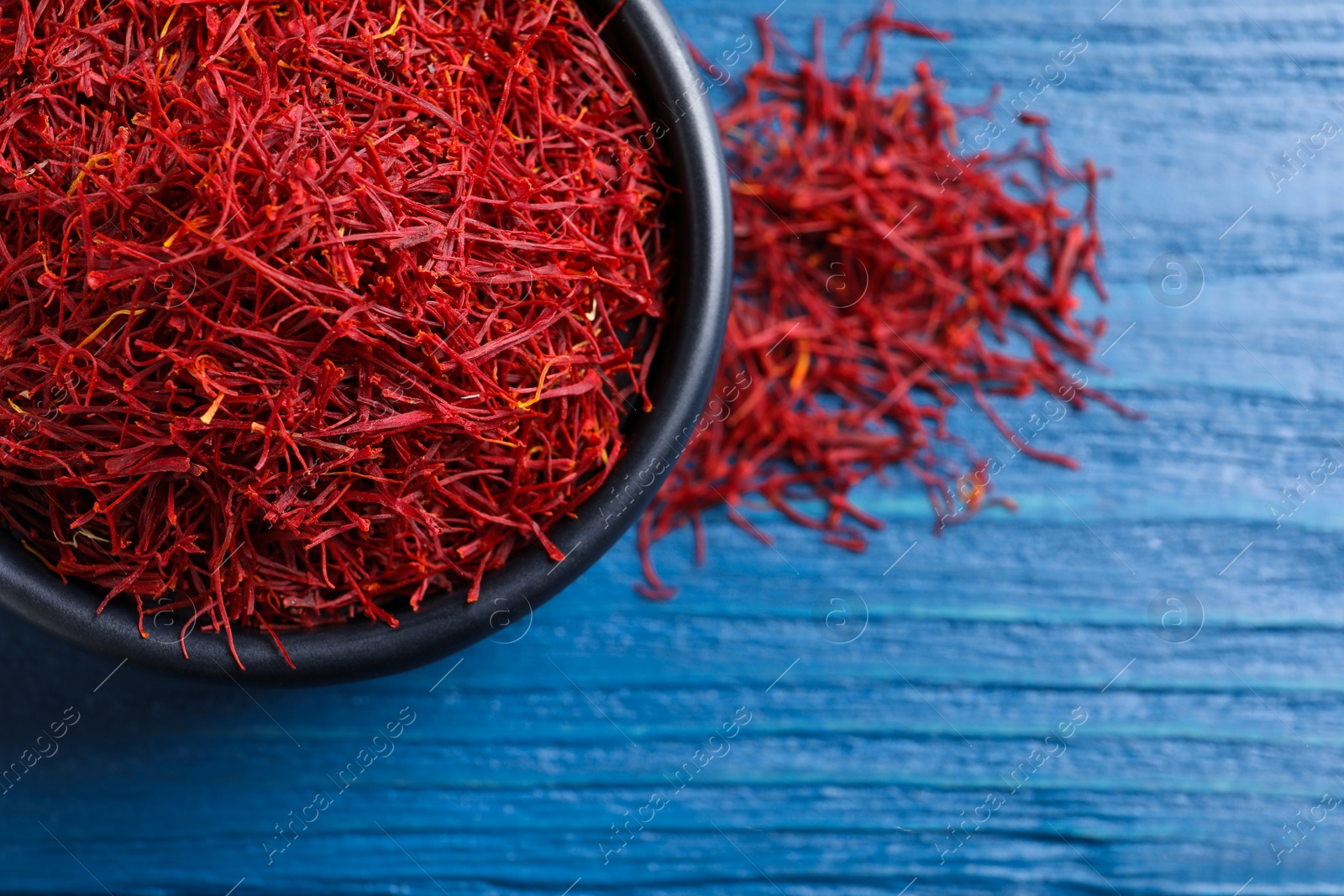 Photo of Dried saffron on blue wooden table, flat lay. Space for text