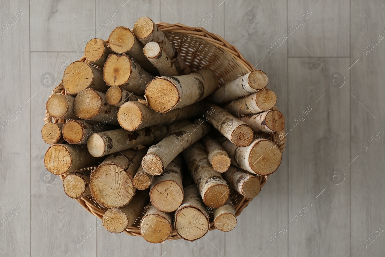 Photo of Wicker basket with firewood on floor indoors, top view