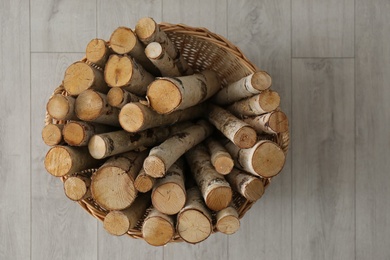 Wicker basket with firewood on floor indoors, top view