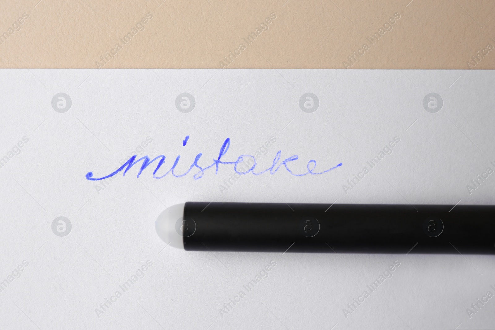 Photo of Word Mistake written with erasable pen on sheet of paper against beige background, top view