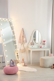 Photo of Large mirror with light bulbs and dressing table in stylish room. Interior design