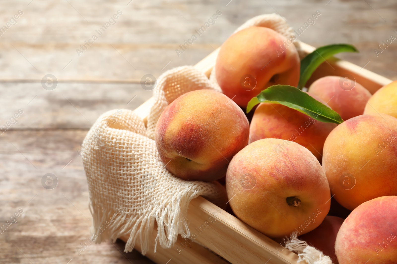 Photo of Wooden crate with fresh sweet peaches on table, closeup