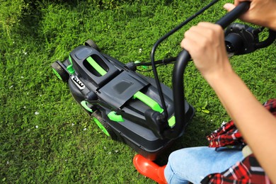 Photo of Woman cutting grass with lawn mower in garden, above view