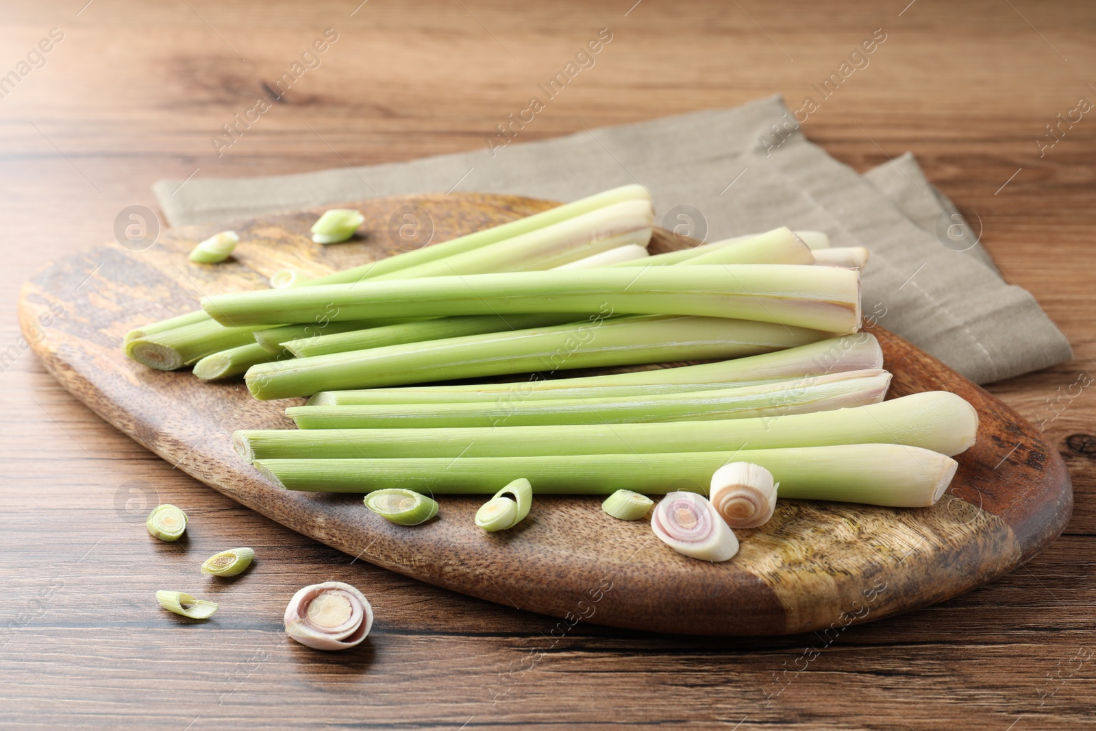 Photo of Board with fresh lemongrass stalks on wooden table