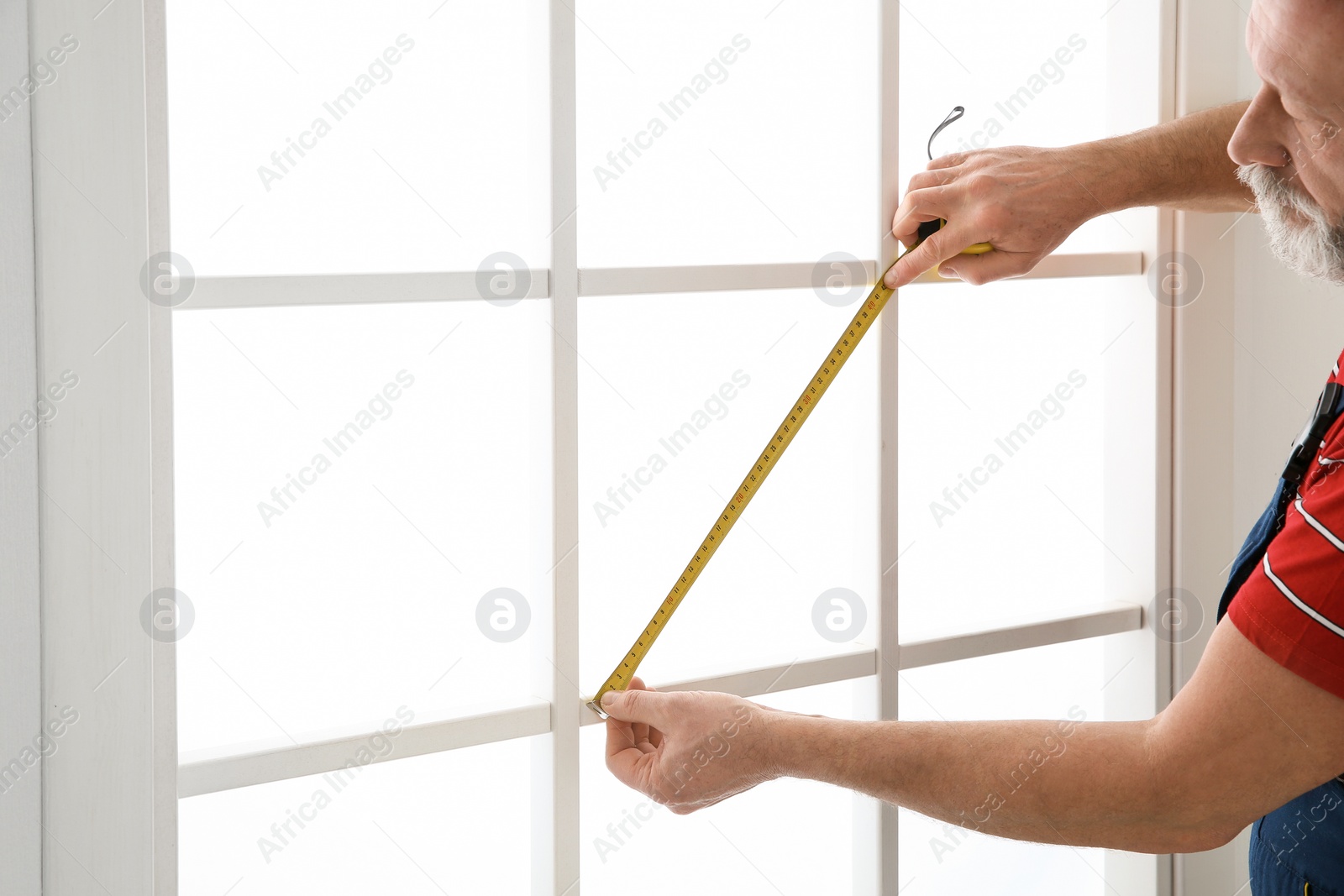 Photo of Service man measuring window for installation indoors