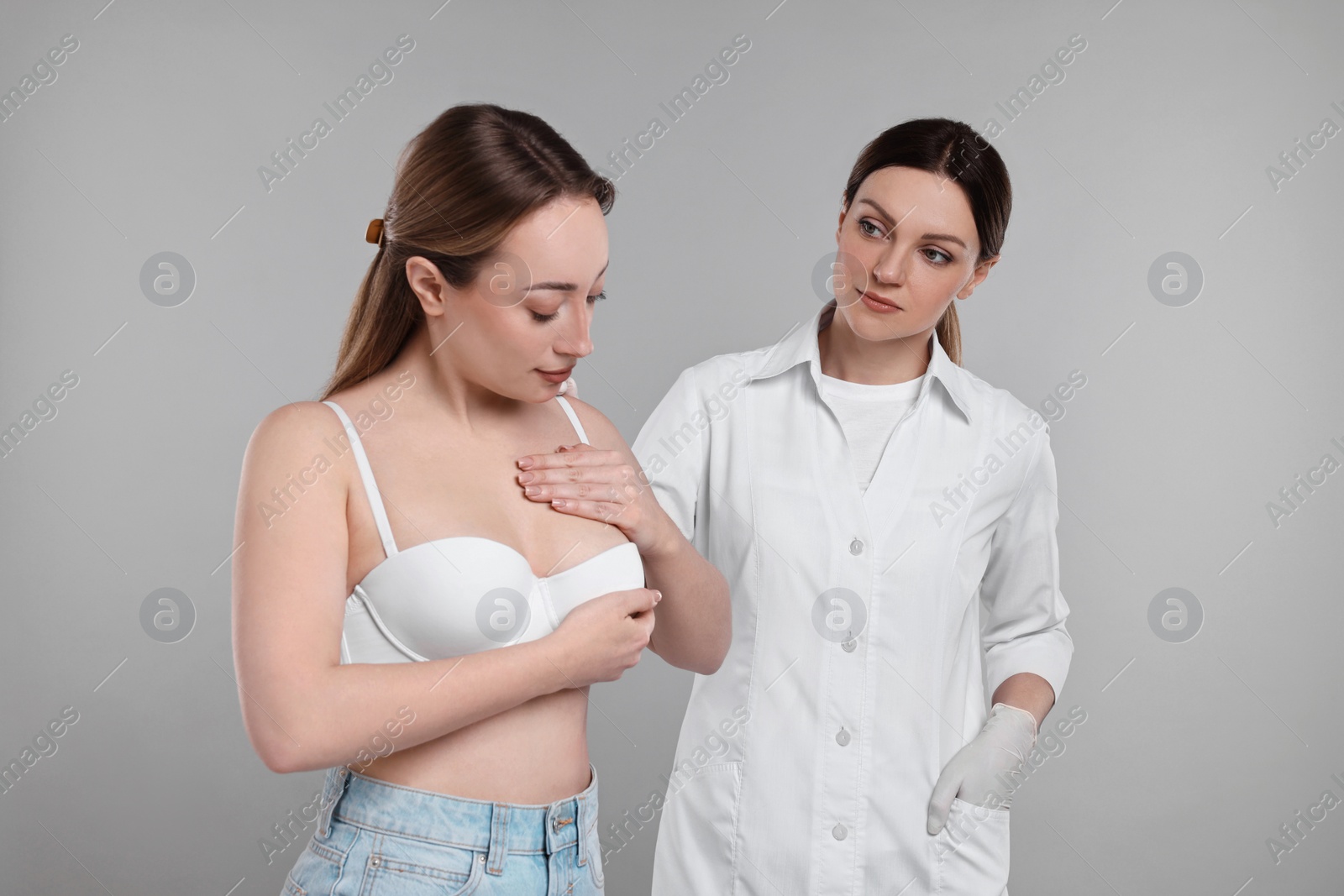 Photo of Mammologist checking woman's breast on gray background