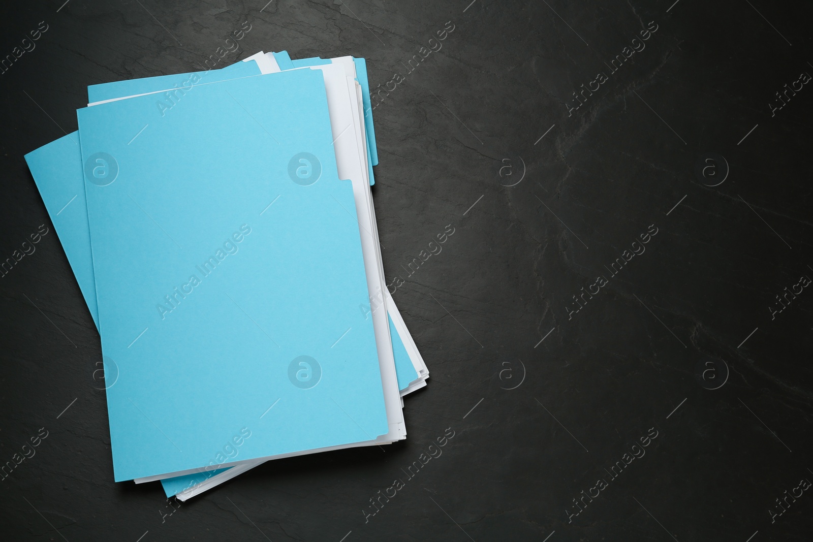 Photo of Turquoise files with documents on black slate table, top view. Space for text
