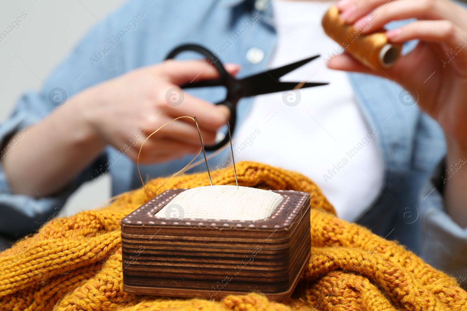 Photo of Woman sewing sweater, focus on pin cushion