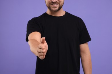 Photo of Man welcoming and offering handshake on purple background, closeup