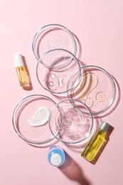 Many Petri dishes and cosmetic products on pink background, flat lay