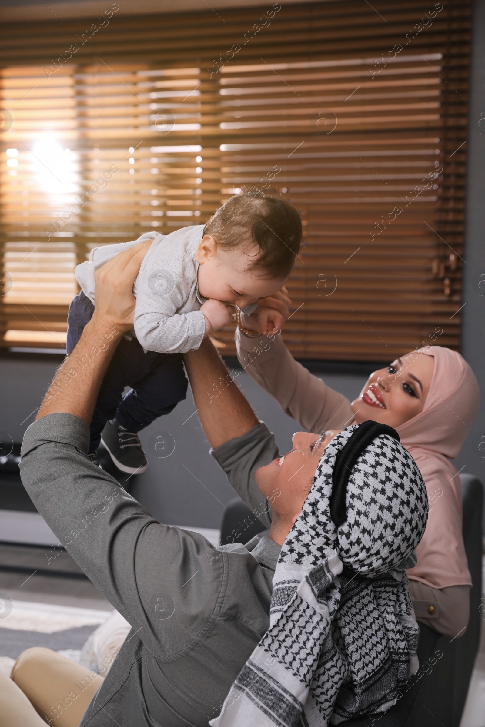 Photo of Happy Muslim family with little son in living room