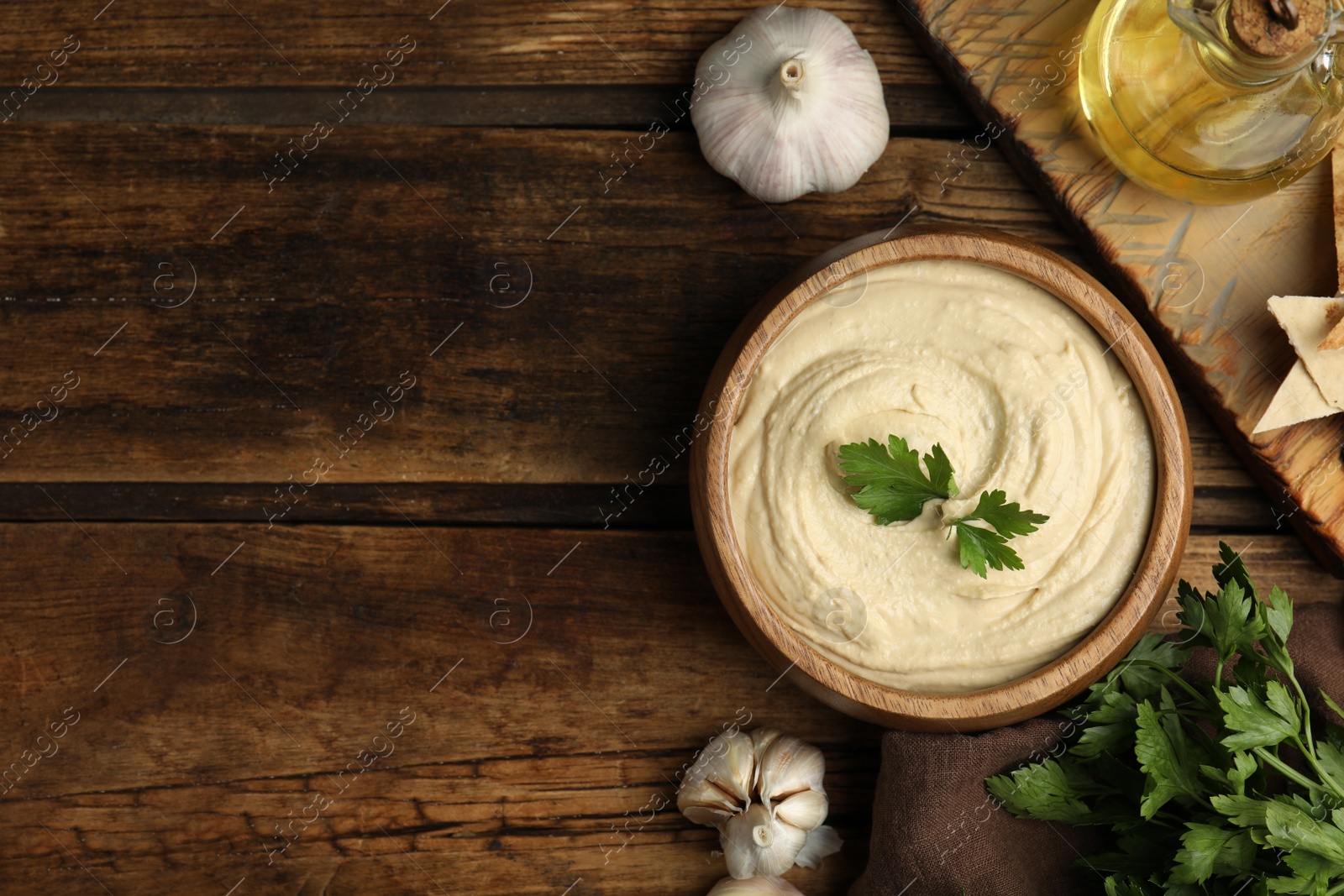Photo of Delicious hummus with parsley on wooden table, flat lay. Space for text