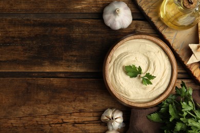 Photo of Delicious hummus with parsley on wooden table, flat lay. Space for text