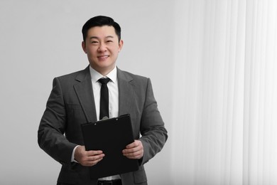 Portrait of happy notary with clipboard indoors, space for text