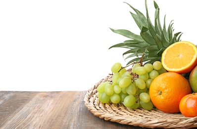 Photo of Wicker mat with fresh tropical fruits on wooden table