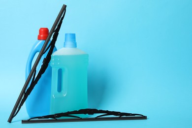 Photo of Bottles of windshield washer fluids and wipers on light blue background. Space for text