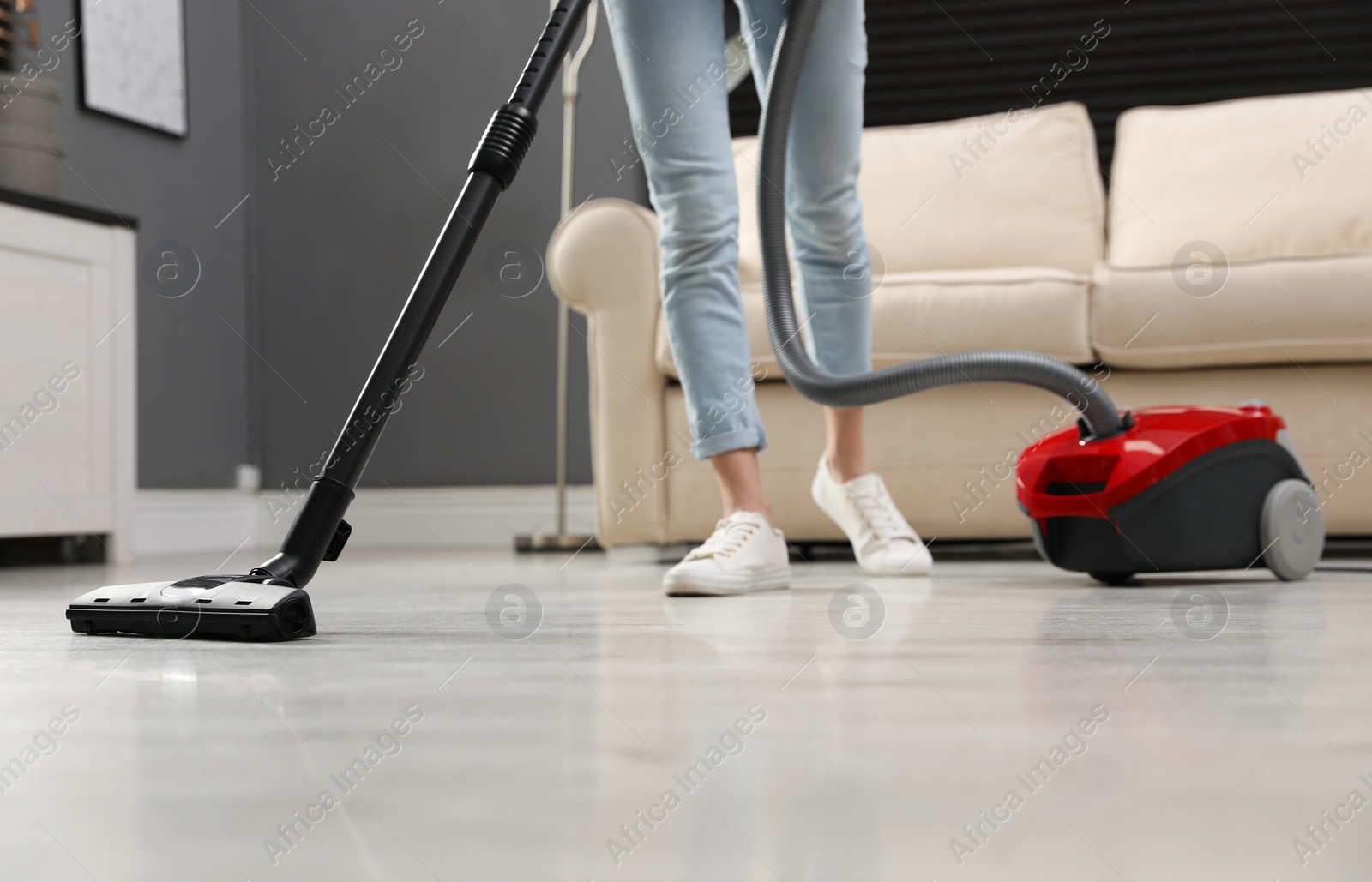 Photo of Young woman using vacuum cleaner at home, closeup