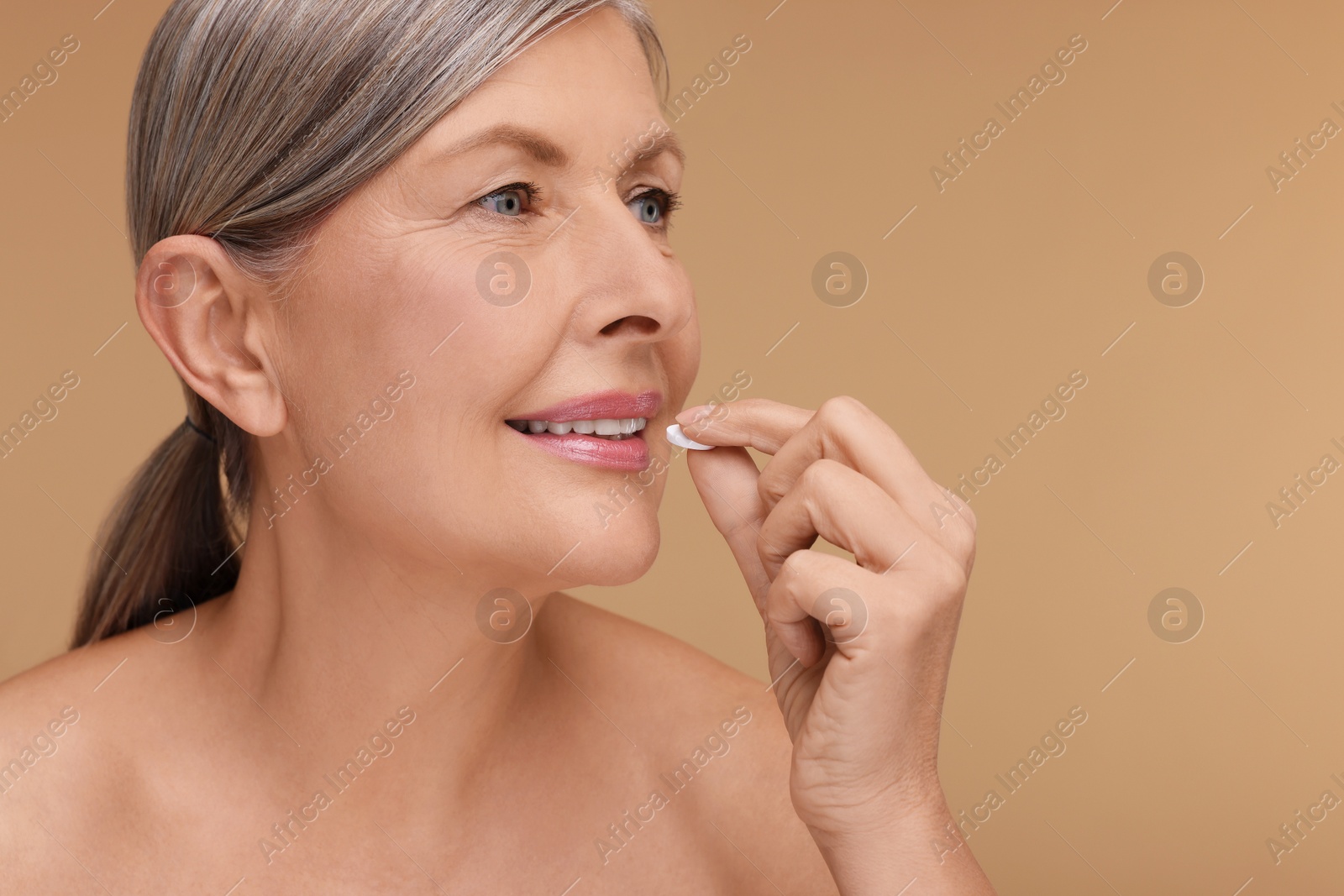 Photo of Beautiful woman taking vitamin pill on beige background, space for text