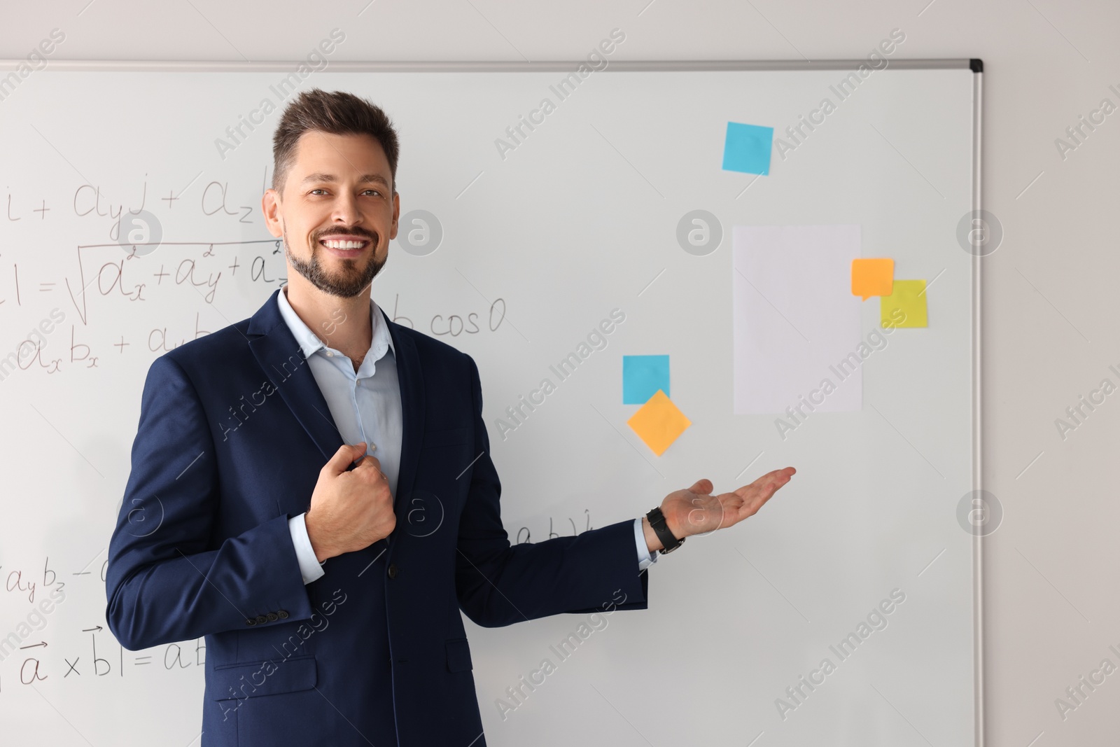 Photo of Happy teacher explaining mathematics at whiteboard in classroom