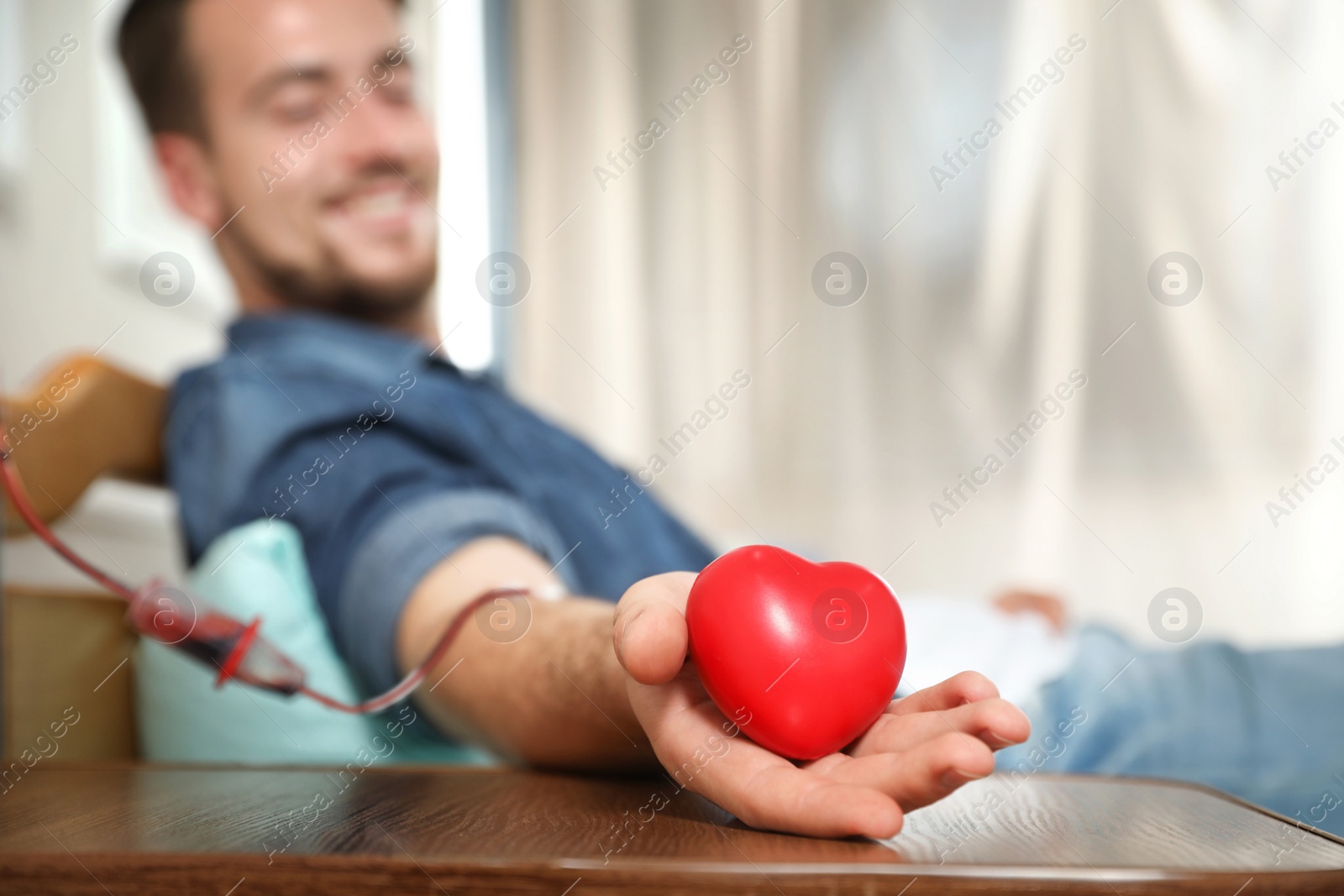 Photo of Young man making blood donation in hospital, focus on hand