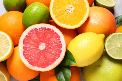 Photo of Pile of different fresh citrus fruits and leaves on table, above view