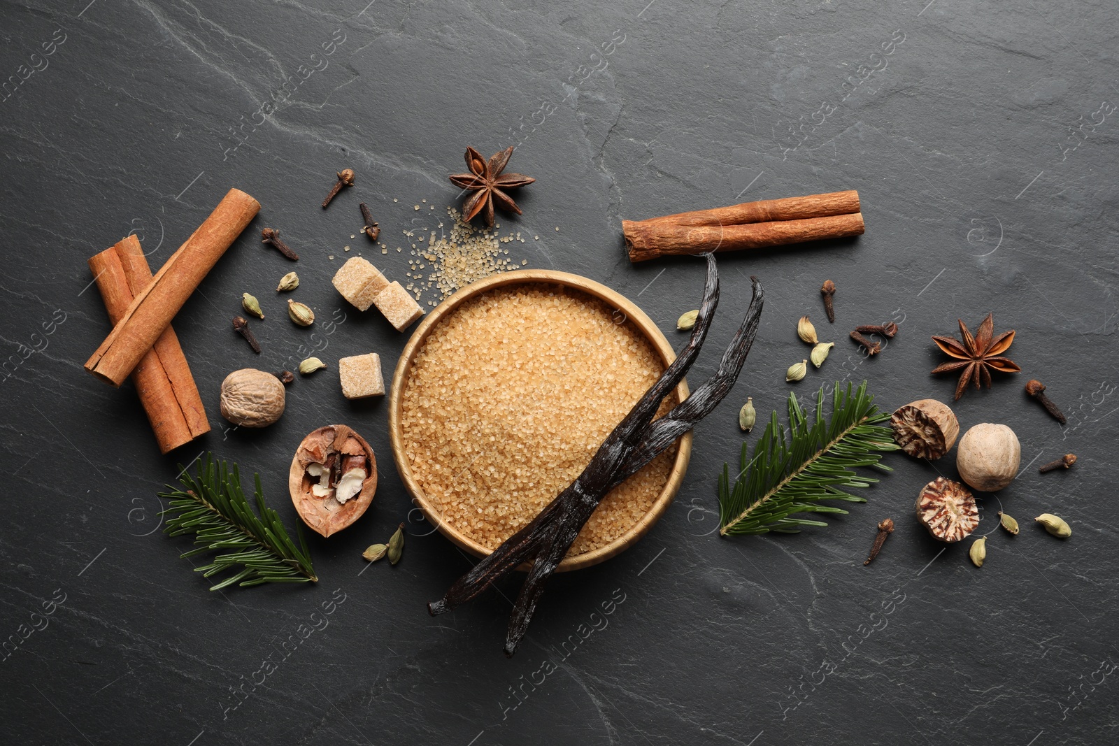 Photo of Different aromatic spices and fir branches on dark textured table, flat lay