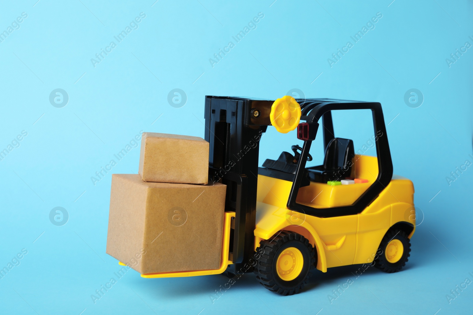 Photo of Toy forklift with boxes on blue background. Logistics and wholesale concept