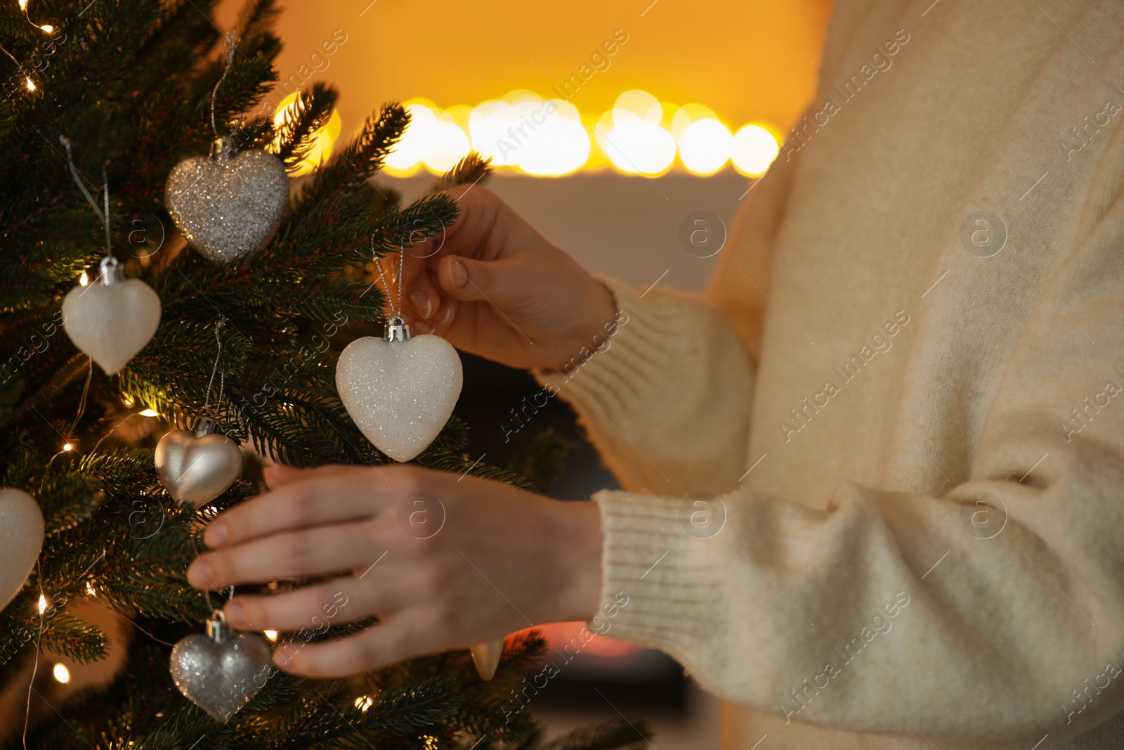 Photo of Woman decorating Christmas tree at home, closeup