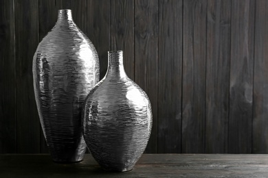 Photo of Stylish silver ceramic vases on black wooden table. Space for text