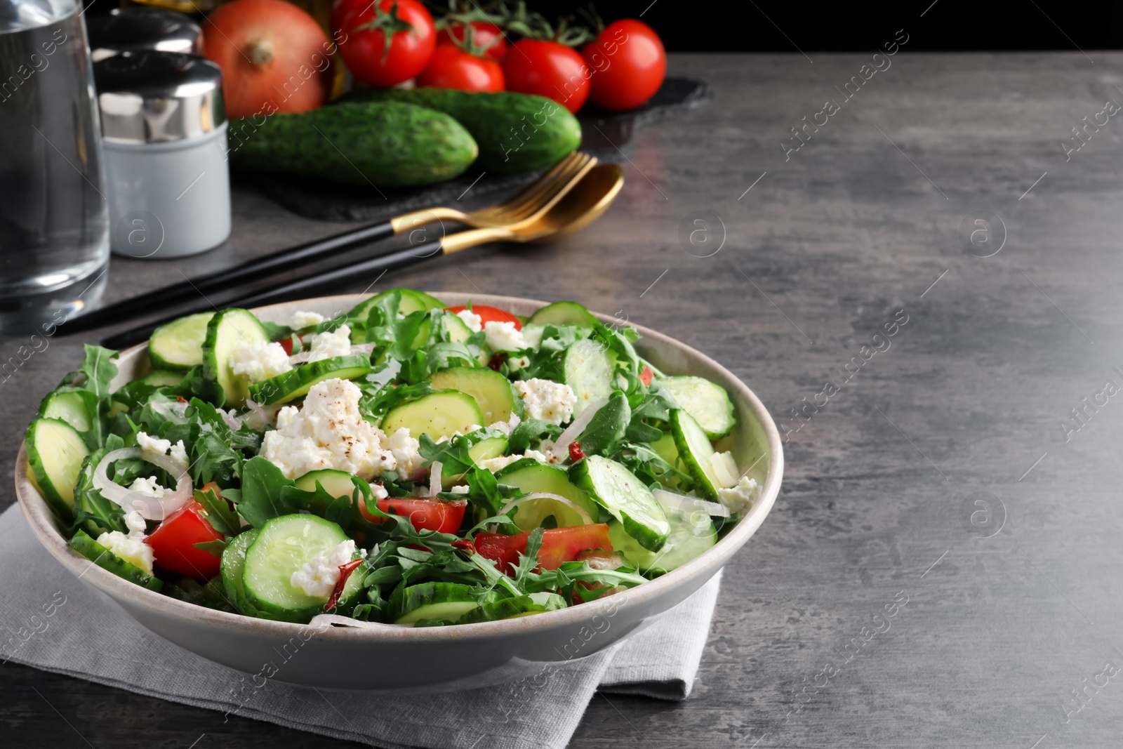 Photo of Plate of delicious cucumber salad served on grey table. Space for text