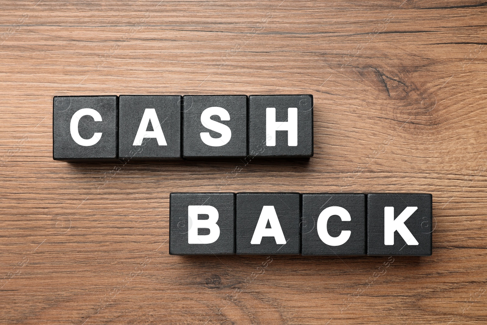 Photo of Black cubes with word Cashback on wooden table, flat lay