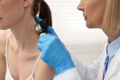 Dermatologist with dermatoscope examining patient in clinic, closeup