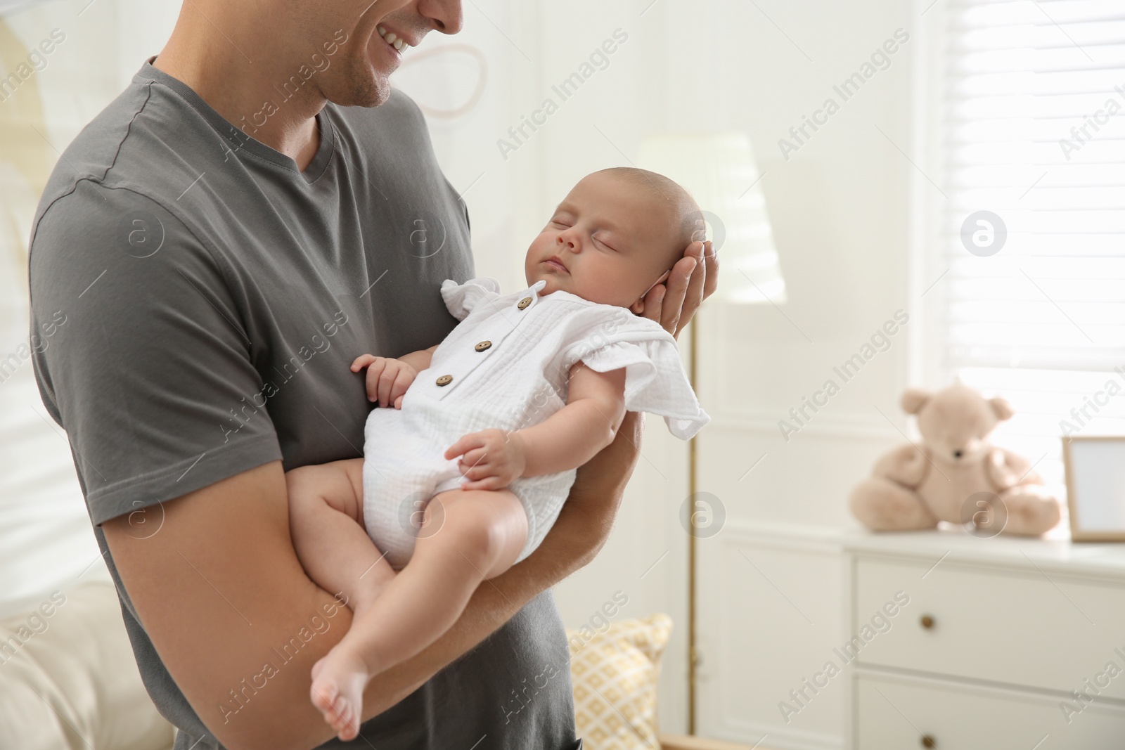 Photo of Father holding his sleeping baby at home, closeup