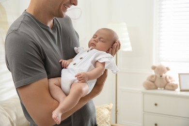 Photo of Father holding his sleeping baby at home, closeup