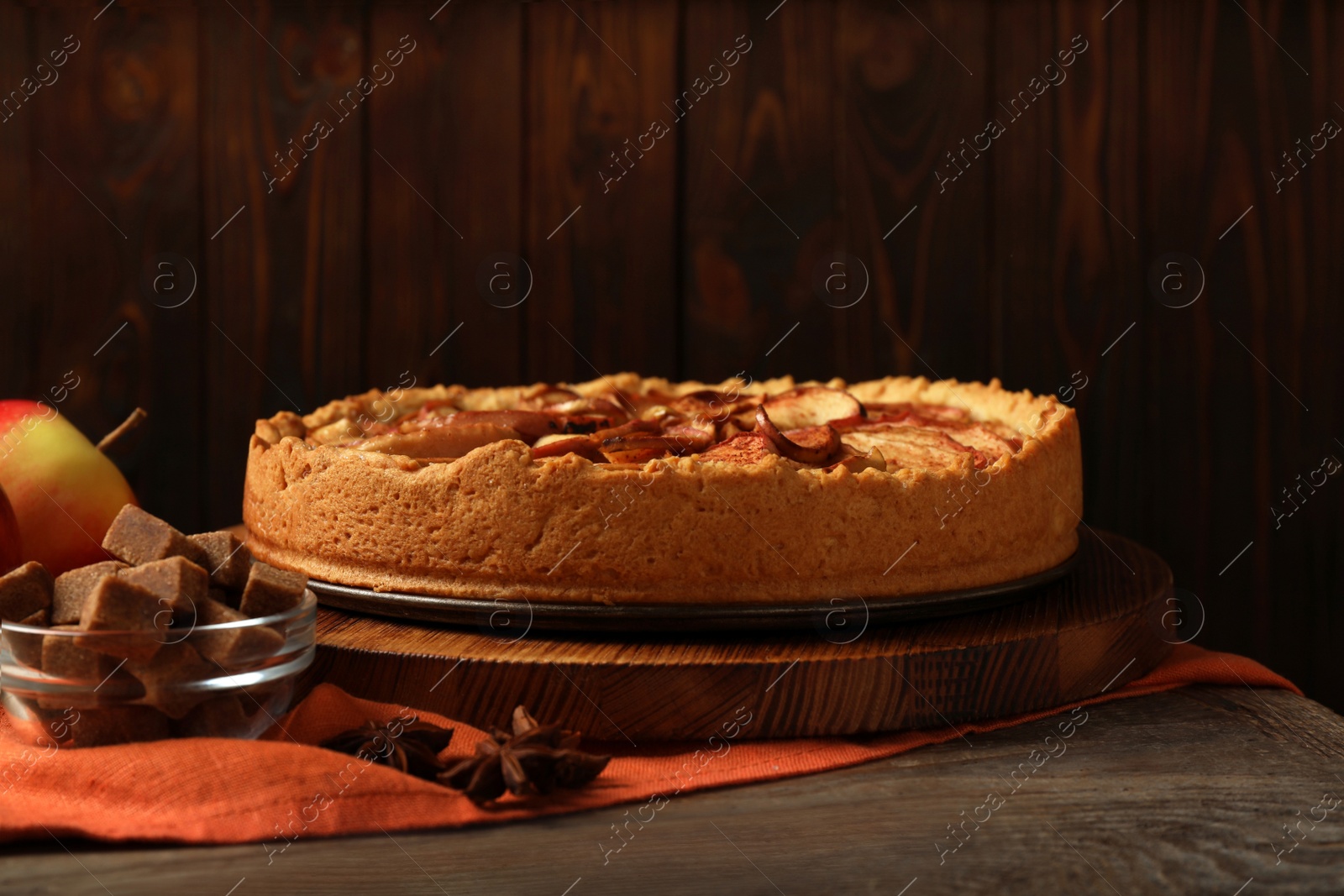 Photo of Delicious apple pie and ingredients on wooden table