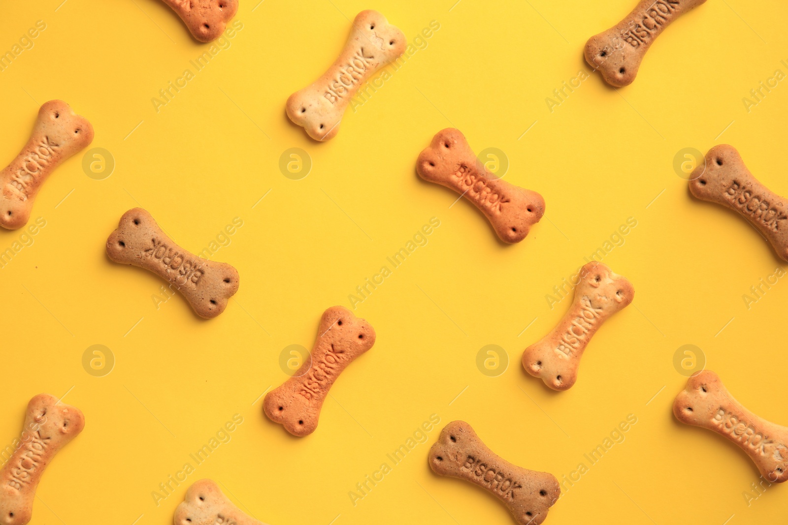 Photo of Bone shaped dog cookies on yellow background, flat lay