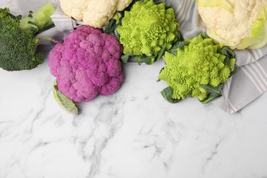 Different fresh cabbages on white marble table, flat lay. Space for text