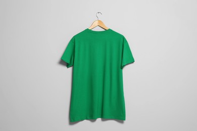 Hanger with green t-shirt on light wall. Mockup for design