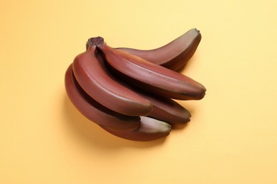 Photo of Tasty red baby bananas on yellow background, top view