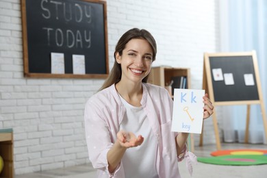 Photo of Happy female English teacher giving lesson in elementary school