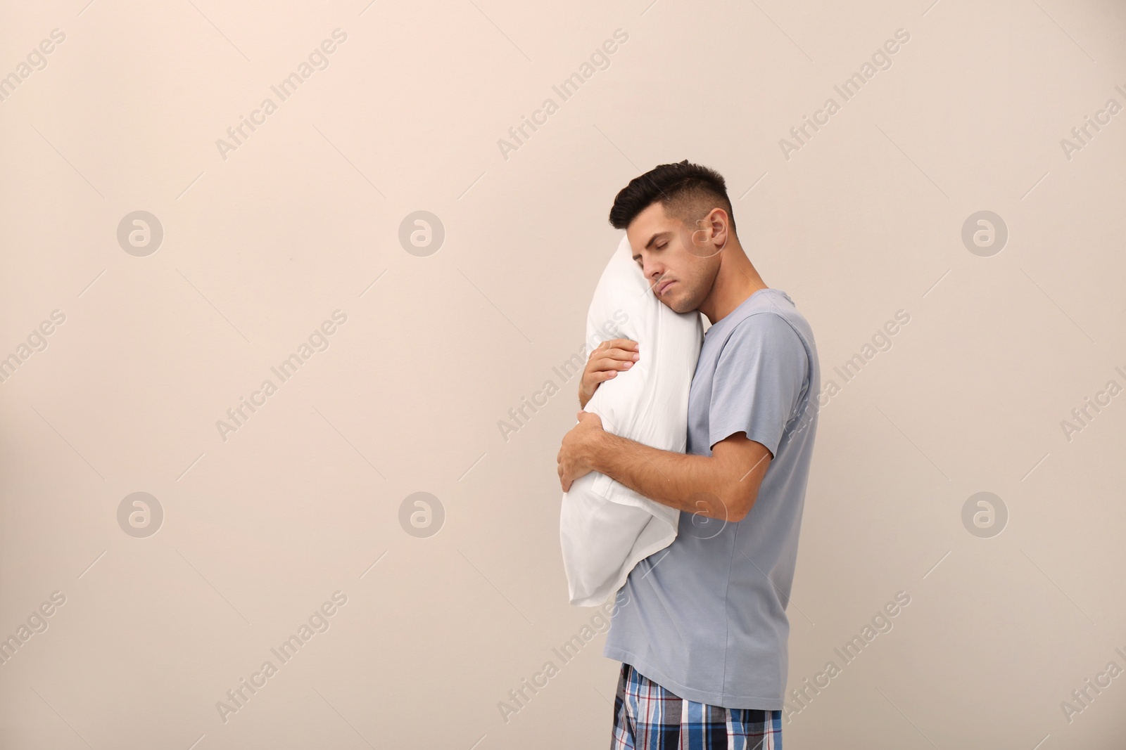 Photo of Somnambulist with soft pillow on beige background, space for text. Sleepwalking