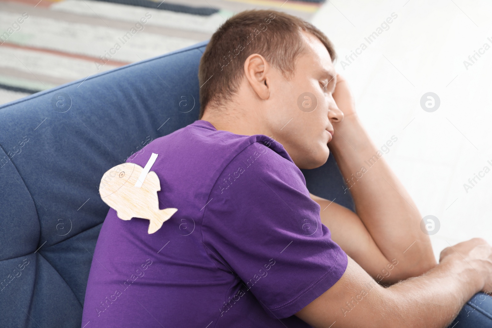 Photo of Sleeping man with paper fish attached to his back on April Fool's Day